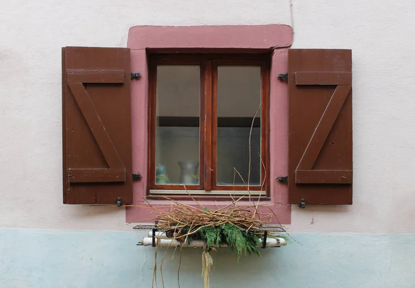 Window with open brown wooden shutters and a metal flower pot on the sill
