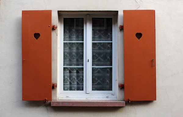 Shutter window with brown doors open on a rural house facade wall