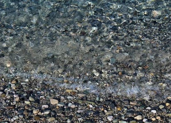 小石や小石で覆われた海岸に打ち寄せる小さな波 — ストック写真