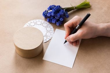Boş kartpostal, adam el yazım kalemi, zanaat giftbox ve muscari (sümbül) çiçek buket mevcut Kraft kağıt üzerinde kapatın