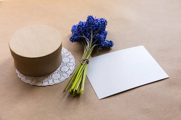 Flatlay boş kartpostal, zanaat mevcut giftbox ve Kraft kağıt üzerinde (sümbül) muscari çiçek buket kapatın