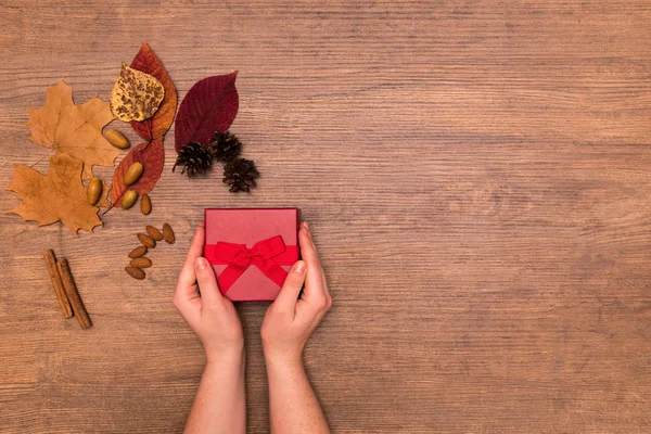 Caixa Presente Vermelha Férias Mãos Mulher Mesa Madeira Com Folhas — Fotografia de Stock