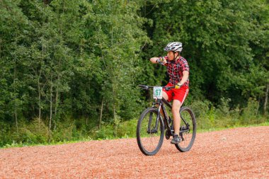 26 Ağustos 2017, Akkesport, Narva, Estonya bisiklet yarışı. Genç katılımcı bisiklete biniyor ve saate bakıyor.
