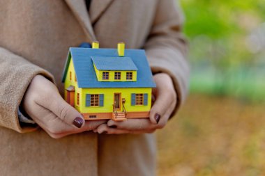 Mini sarı ev modeli ipotek teklifleri için kadınların elinde ve emlak veya iç tasarım satın alarak tasarruf edilen para