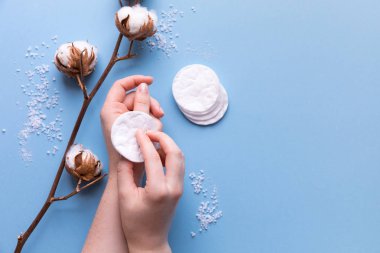 Pamuk tamponlarla kadın el ile kaldırma makyaj çiçekler düz mavi zemin üzerine Pamuk