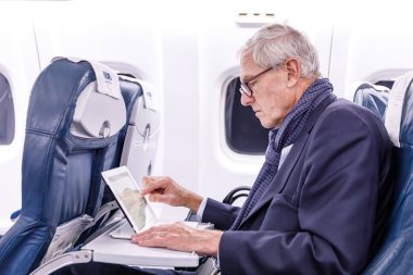 Ekim 2017, Finnair uçağı St. Petersburg-Helsinki. Saygıdeğer yaşlı bir adam bir tablette haber okuyor.