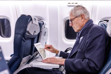 Ekim 2017, Finnair uçağı St. Petersburg-Helsinki. Saygıdeğer yaşlı bir adam bir tablette haber okuyor.