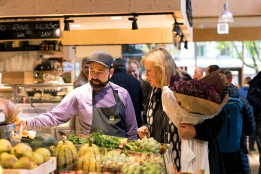 Ekim 2017, Stockholm, İsveç 'te Gıda Pazarı Ostermalmtorg. Kadın ve çiftlik satıcısı sebzelerden bahsediyor.