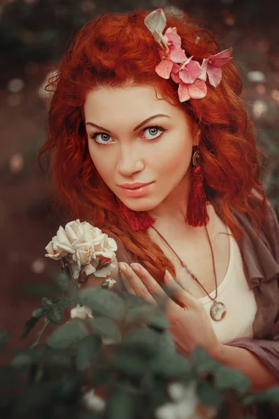Červené vlasy dívka v růžové zahradě — Stock fotografie