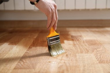 Paintbrush ile vernikleme parke zemin - ikinci katman. Ev yenileme parke. Ahşap parke üzerinde vernik boya fırçası darbeleri. Son derece parlak parke cilası uygulaması