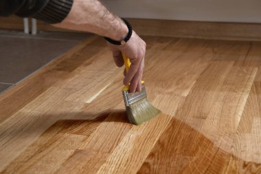Varnishing lacquering parquet floor by paintbrush - second layer. Home renovation parquet. Varnish paintbrush strokes on a wooden parquet. Application of a highly glossy parquet lacquer clipart