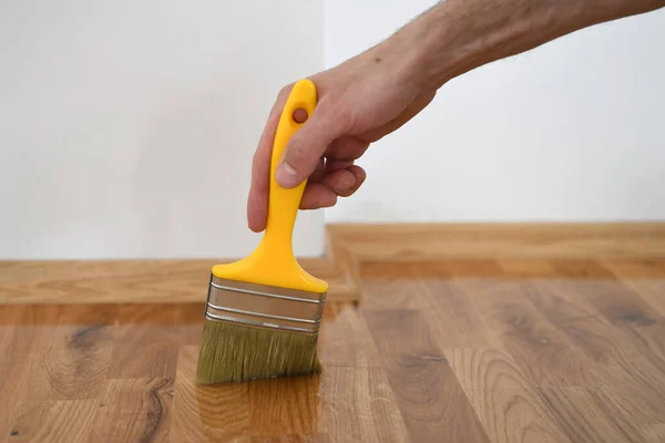 漆木地板 工人用刷子刷地板 用漆刷 第二层涂漆地板 家庭装修宴会 — 图库照片