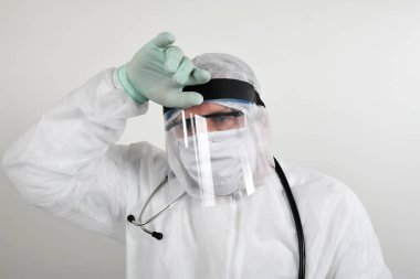 Yetişkin erkek doktor uzun saatler çalışıyor. Doktor ceketli ve steteskop takmış beyaz arka planda duran yorgun ve bunalımda kollarını çapraz tutmaktan sıkılmış görünen bir doktor.