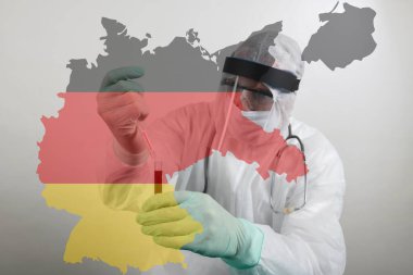Solunum maskesi takan ve Coronavirus Covid-19 kan örneğini elinde tutan bir doktor. Bilim adamları Covid-19 ya da Corona virüsü için test yapıyorlar. Fotoğraf üzerinde Almanya 'nın şeffaf bayrağı