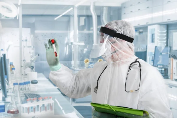 Solunum maskesi takan ve Coronavirus Covid-19 kan örneğini elinde tutan bir doktor. Hastane kliniğinde kan örnekleriyle çalışan bir doktor. 