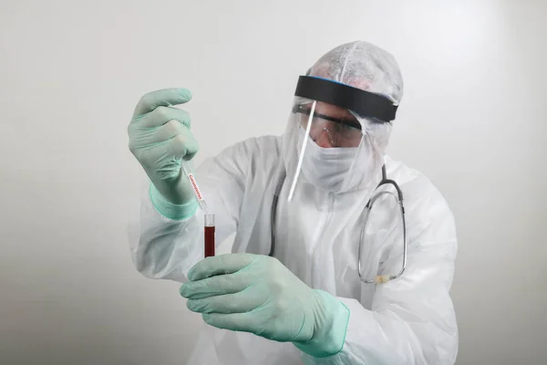Solunum maskesi takan ve Coronavirus Covid-19 kan örneğini elinde tutan bir doktor. Bilim insanları Covid-19 ya da Corona virüsünü laboratuvar ya da hastanede hastalıkları araştırmak ve tedavi etmek için bilim tüplerini kullanarak test ediyorlar. Tıbbi tedavi kavramları