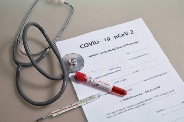 COVID-19 testinden sonra tıbbi sertifika. Üzerinde stetoskop, termometre ve kan testi COVID-19 nCoV-2 olan tıp belgeleri.
