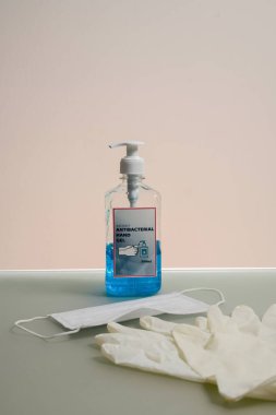 Bir şişe temiz sıvı antibakteriyel el jeli. Antibakteriyel el dezenfektan, tıbbi eldiven ve maske.
