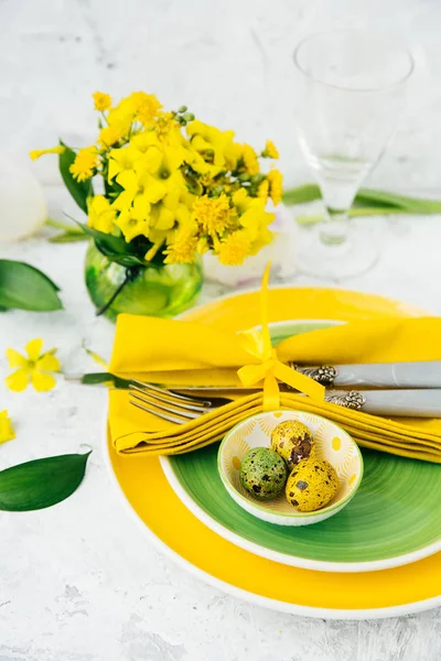 Feestelijke tafel instelling en decoratie met verse bloemen in groen en geel. Pasen-achtergrond — Stockfoto