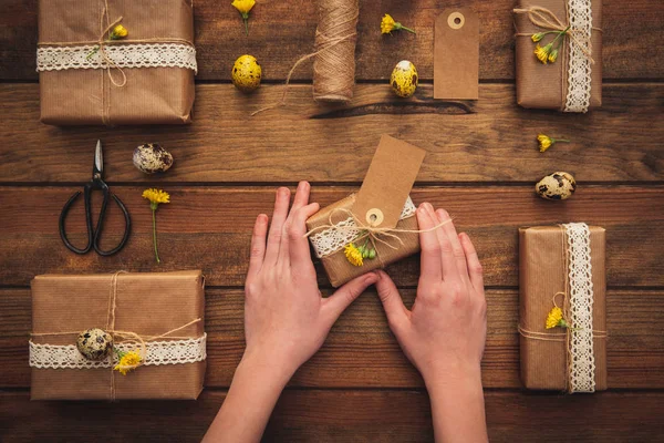 Manos sosteniendo caja de regalo sobre fondo de madera. Concepto de Pascua. Vista superior — Foto de Stock