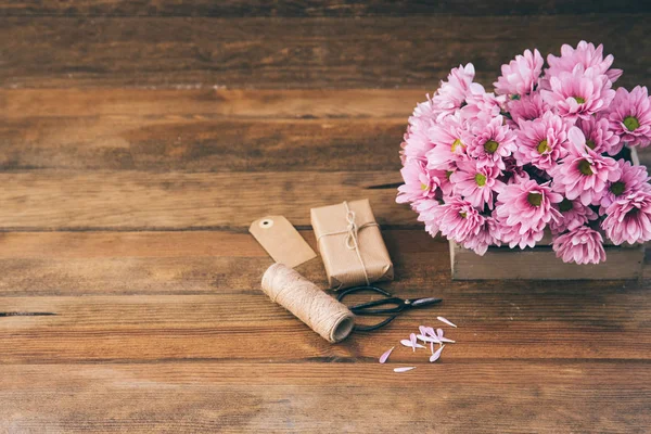Stillleben mit Blumen und Geschenk über Holzgrund. Raum für Text — Stockfoto
