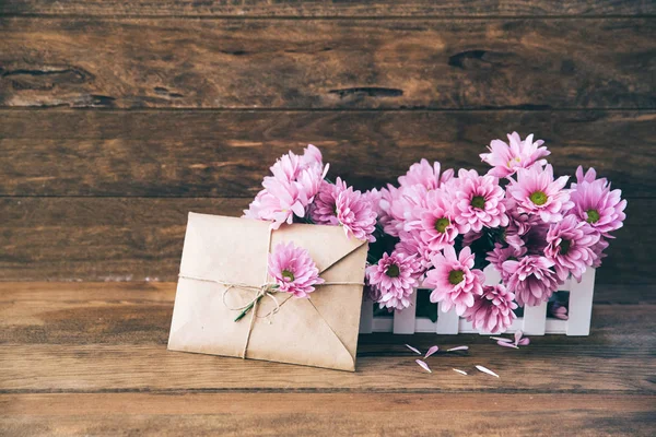 Vakantie achtergrond met tuin bloemen en ambachtelijke envelop op houten tafel — Stockfoto