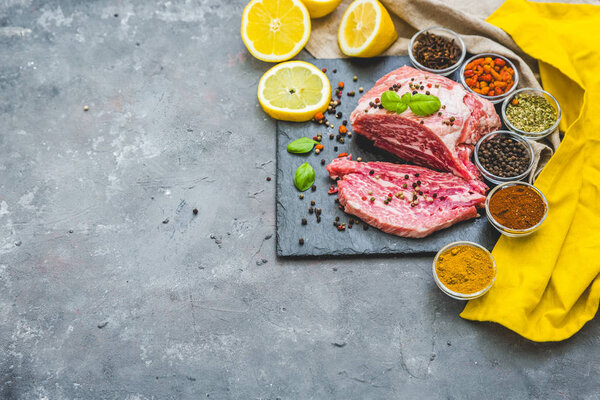 Raw fresh meat steak with spices on grey background