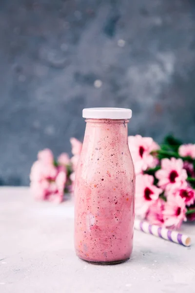 Smoothie in milk bottle with flowers over vintage background — Stock Photo, Image