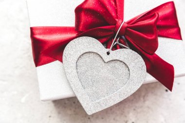 Şerit ve antika arka plan üzerinde kırmızı kalp ile hediye bağlıdır. Sevgililer günü