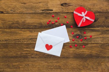 Boş Sevgililer tebrik kartı ve küçük kırmızı hediye kutusu ahşap masa üzerinde. Aşk mektubu