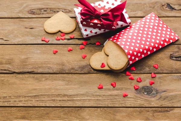 Heart shaped cookies with gifts over wooden background. Valentine day - homemade festive decorated pastry biscuits cookies