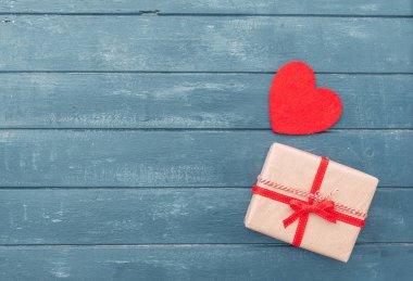 Ahşap arka plan üzerinde kırmızı kalp ve Hediyelik kutu. Mutlu Sevgililer günü