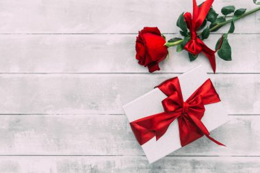 Kırmızı gül ve ahşap bir masa üzerinde hediye kutusu
