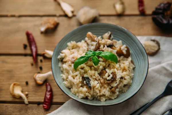 Risotto and mushroom dish in bowl over wooden table