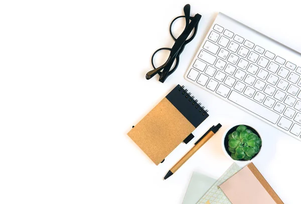 Home Office Desktop with keyboard, notepad, flower and glass. Flat lay, top view