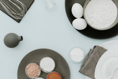 Pişirme malzemelerin üzerine pastel arka plan. Üstten Görünüm, düz yatıyordu, kopya alanı. Süt, un, şeker, yumurta, tereyağı, zeytinyağı, toz kakao, kabartma tozu, vanilya ve sirke hazırlık pişirme mutfak masası 