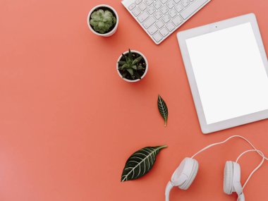 Üstten Görünüm yaratıcı kadının masaüstü, beyaz tablet ve kulaklık ile boş kopya alanı perde. Yukarı alay, yatıyordu, pembe pastel arka plan düz  