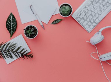 Kadın ev ofis Resepsiyon çalışma dizüstü bilgisayar, kulaklık ve bitkiler üzerine pastel. Düz yatıyordu, en iyi görünüm. şık kadın kavramı.