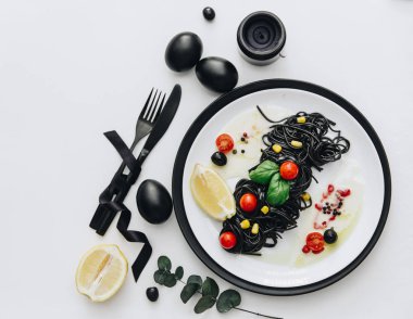 Siyah spagetti Bazilikası'nın ve domates masada. Siyah Paskalya yumurtaları. Düz yatıyordu, en iyi görünümü