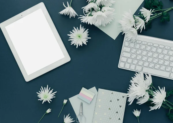 Minimalist workspace. Tablet, keyboard with spring flowers on pastel background. top view, flat lay