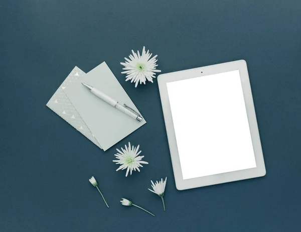 Minimalist workspace. Tablet with spring flowers on pastel background. top view, flat lay