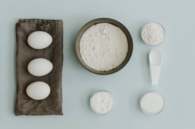 Taze yumurta, kabartma tozu, şeker ve un pastel arka plan üzerinde. Düz yatıyordu minimalist fırın arka plan 