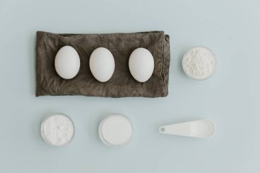 Taze yumurta, kabartma tozu, şeker ve un pastel arka plan üzerinde. Düz yatıyordu minimalist fırın arka plan 