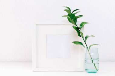 Mockup çerçeve yeşil dallar üzerinde en az arka plan masaya vazoda. Ev dekorasyonu. Blog, Web sitesi veya sosyal medya kavramı.