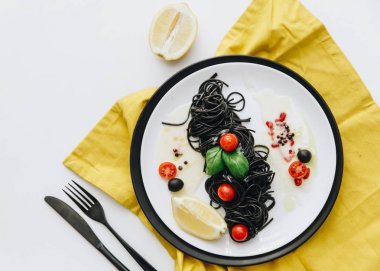 Squid mürekkep ve sarı peçete ile beyaz tabloda salat ile makarna. Üstten Görünüm, düz yatıyordu 