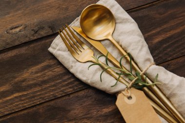 Altın çatal bıçak takımı. Çatal ve bıçakla rustik ahşap masa peçeteye.