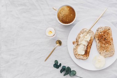 Düz keten masa günü kahvaltıda tereyağı ve kahve ile toast Lay