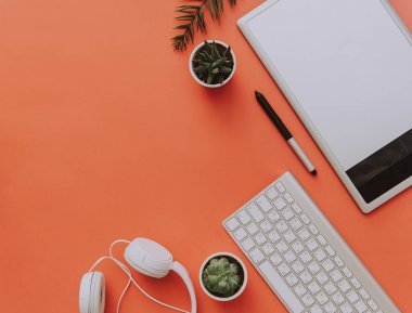 Tasarımcı, blogger çalışma tablosu üstten görünüm. Grafik tablet, klavye, kulaklık beyaz masaya döşeme.