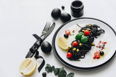 Siyah spagetti Bazilikası'nın ve domates masada. Siyah Paskalya yumurtaları. 