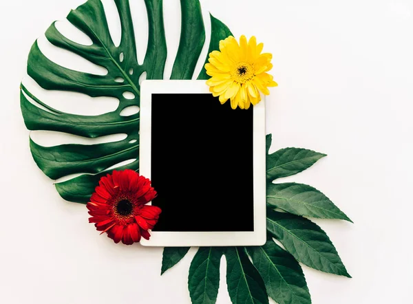 Düz yatıyordu dijital tablet tropikal yaprak ve çiçek ile. Yaz sunu kavramı 